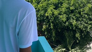 A person standing on a balcony overlooking a cityscape with buildings and greenery. - Miami Beach Hostel (Cartagena de Indias)
