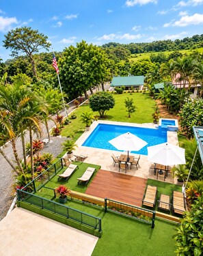 A swimming pool with a patio area, surrounded by lush greenery and a view of a hilly landscape. - NEW! Moody’s – Your Little Piece of Paradise (Savegre)