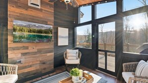 Una habitación acogedora con paredes de madera, un ventanal grande y un ventilador de techo.