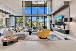 A spacious living room with a large sofa, a coffee table, and a TV mounted on the wall. - Coral Heaven | Las Olas Waterfront Estate | Dock (Fort Lauderdale)