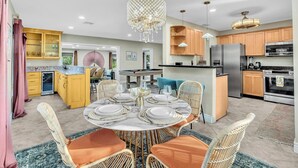 Une cuisine moderne avec un coin repas, comprenant une table en marbre, des chaises en osier et un lustre.