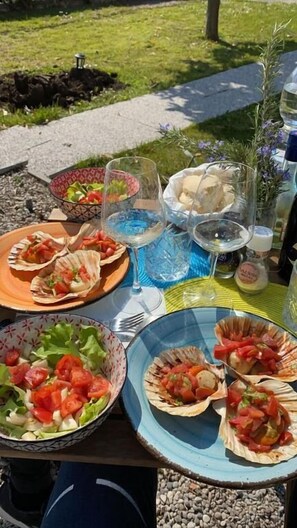 A table set outdoors with plates of food, glasses of water, and a bottle of wine. - Hotel Orio (Venice)