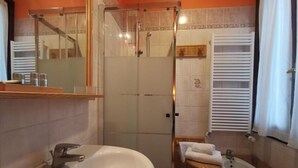 A bathroom with a large bathtub, a smaller sink, a glass-enclosed shower, and a towel rack. - Hotel Orio (Venice)