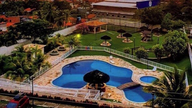 Un complex turístic amb diverses piscines, un edifici gran i vistes al capvespre.