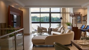 Un salon moderne doté d’une grande fenêtre, d’un canapé, d’une table basse et d’un coin repas avec une table à plateau en verre.