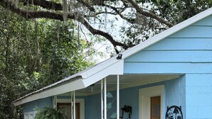 Una casa azul con porche, un cartel de bienvenida y un pequeño jardín.