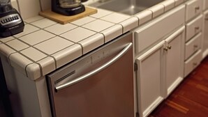 A kitchen with white cabinets, a stainless steel dishwasher, a coffee maker, and a sink. - Beautiful Gated 2-bedroom 1 bath Condo with fireplace in fabulous Hayward. (Hayward)