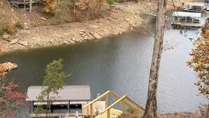 A cabin with a dock extending into a calm lake, surrounded by autumn foliage.