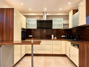 A modern kitchen with a central island, stainless steel appliances, and wooden cabinetry.