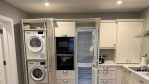 Una cocina compacta con electrodomésticos integrados, encimera de mármol y comedor con sillas de cuero.