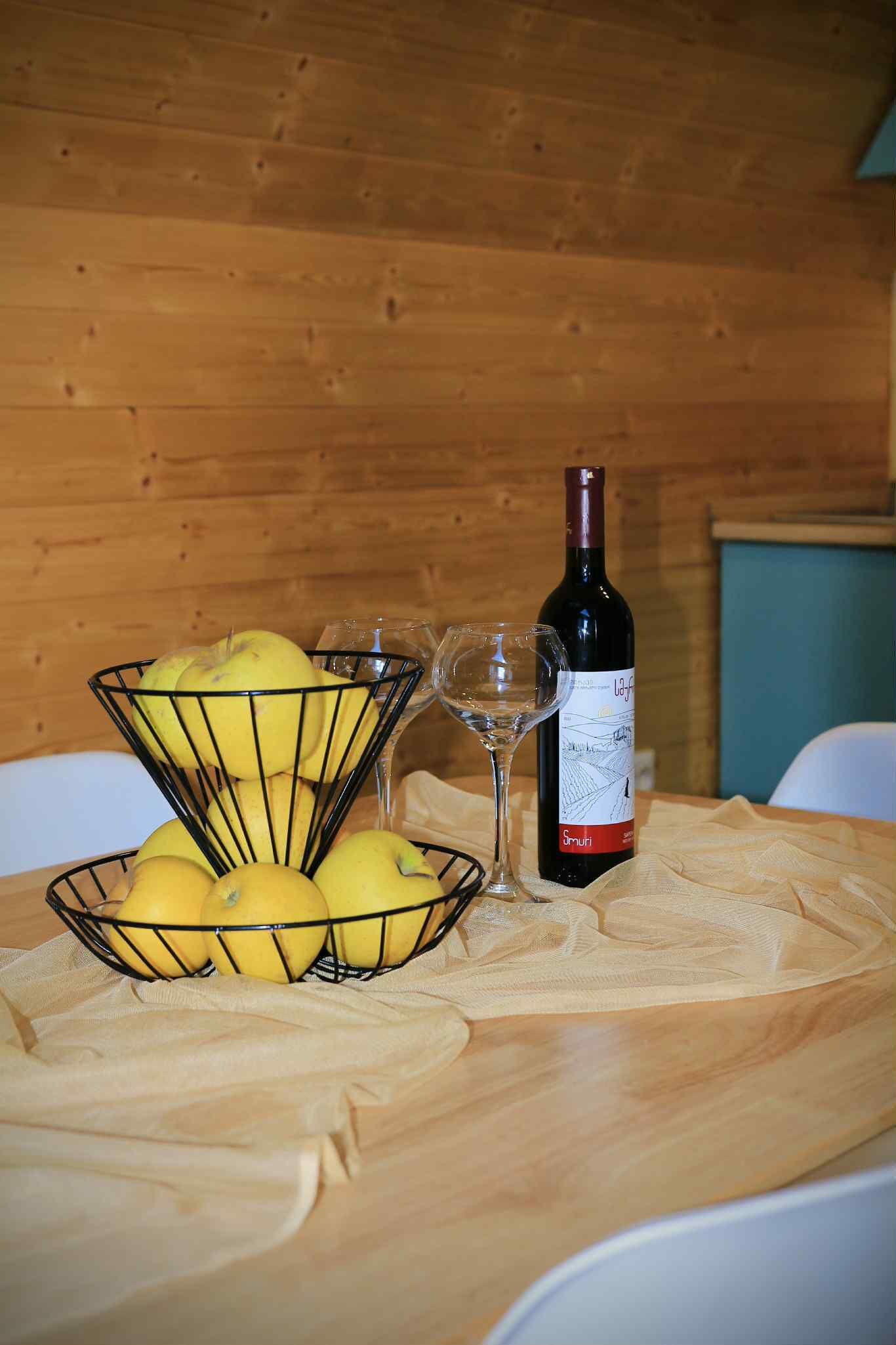Un intérieur en bois avec une table sur laquelle se trouve un panier en fil rempli de citrons et une bouteille de vin.