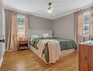 Un dormitorio con una cama, una mesita de noche, un escritorio y un ventilador de techo.