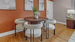 Un coin repas avec une table ronde, quatre chaises et trois tableaux abstraits accrochés au mur.