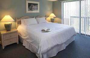 A neatly made bed with white linens and pillows, two bedside lamps, a small bedside table with a lamp, and a framed picture on the wall. - Gorgeous 3-bedroom condo with AC in Hilton Head Island
Playground Near The Beach (Hilton Head Island)