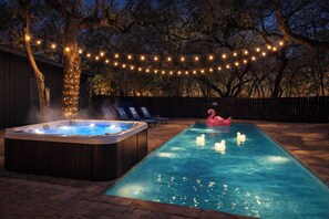 Une piscine avec un jacuzzi, des chaises longues et un flotteur en forme de flamant rose.