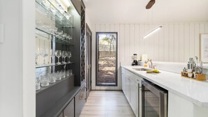 Eine moderne Küche mit einem Gläser-Weinschränkchen, Edelstahlgeräten und Blick ins Freie.