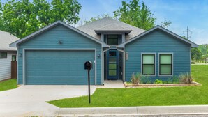 A two-story house with a blue garage, a front entrance, and a mailbox. - Modern Lake Escape Arcade EV Fun (Denison)
