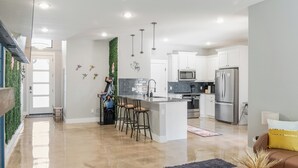A modern kitchen with white cabinets, stainless steel appliances, and a central island with bar stools. - Modern Lake Escape Arcade EV Fun (Denison)