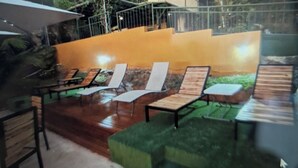 A modern building with a glass facade, outdoor seating area with lounge chairs, and a pool. - Moody's Huts. 1-bedroom house in Savegre with AC, 5 minutes from Dominical Beach (Savegre)