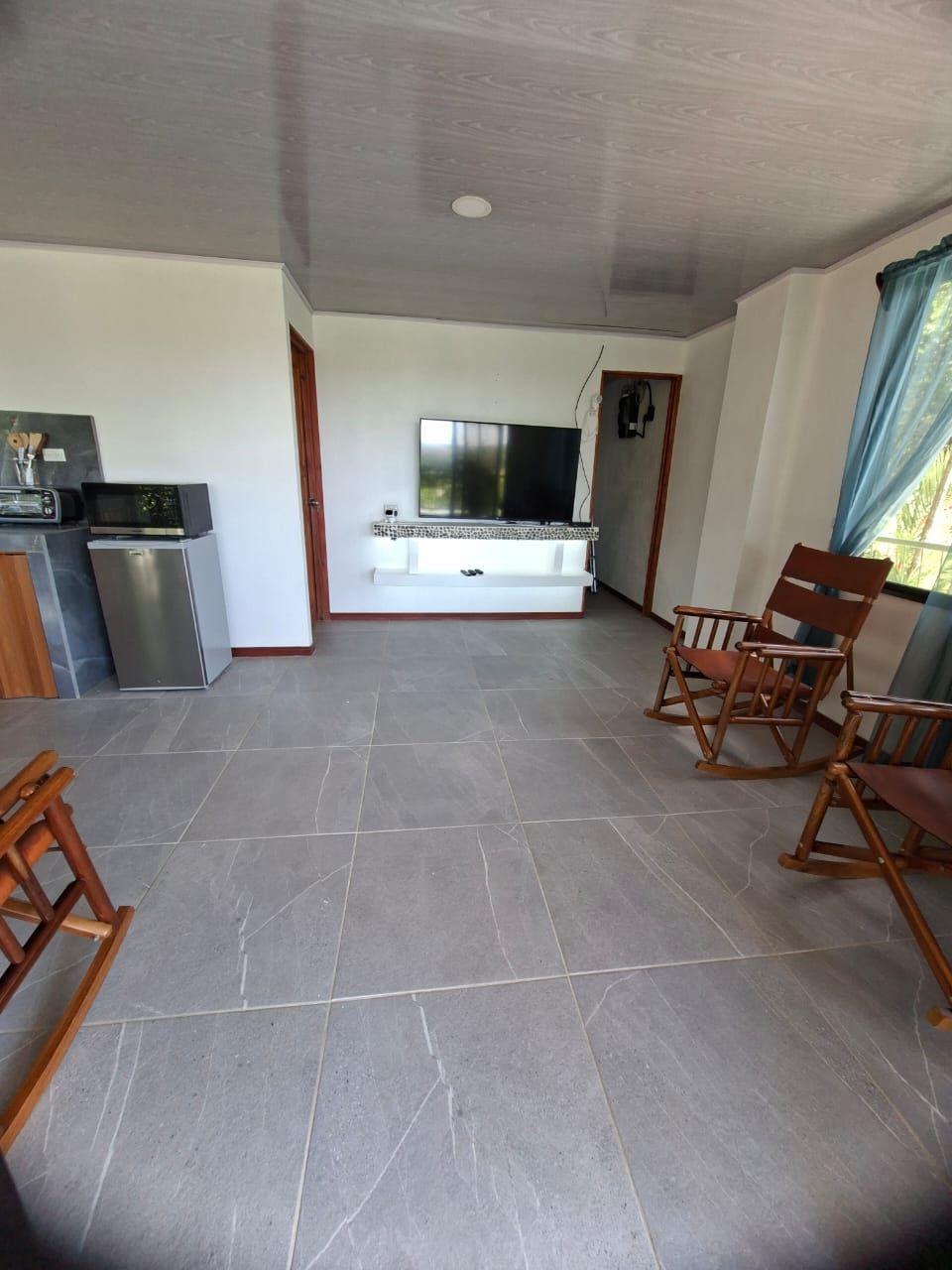 Ein geräumiger Wohnbereich mit Flachbildfernseher, eingebautem Kamin und einer Sitzecke mit Holzsesseln.