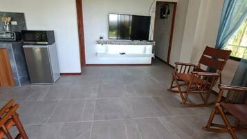 Ein geräumiger Wohnbereich mit Flachbildfernseher, eingebautem Kamin und einer Sitzecke mit Holzsesseln.