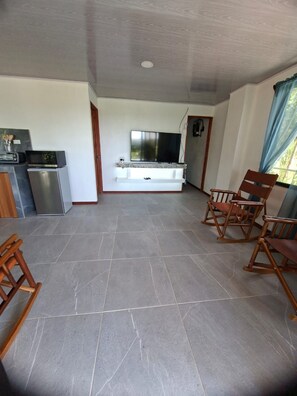 A spacious living area with a flat-screen TV, a built-in fireplace, and a seating area with wooden chairs. - NEW Moody's Huts -Savegre Surf House (Savegre)