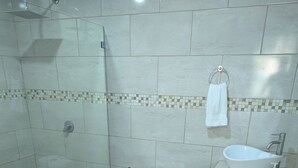 A bathroom with a shower, toilet, sink, and a towel rack. - Moody's Huts. 1-bedroom house in Savegre with AC, 5 minutes from Dominical Beach (Savegre)