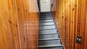 Una escalera de madera con barandilla que lleva a una puerta blanca en la parte superior.