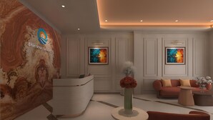 A hotel reception area with a marble wall, a reception desk, two framed abstract paintings, a red sofa, and a small table with a vase of flowers. - Binh Minh Sapa Hotel (Sa Pa)