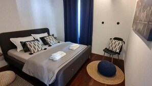 A neatly arranged bedroom with a bed, pillows, a chair, a hat, and a painting on the wall. - Bella Vita - Apartment with free parking (Zagreb)