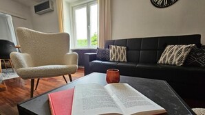 A living room with a black sofa, a beige armchair, a coffee table, and an open book. - Bella Vita - Apartment with free parking (Zagreb)