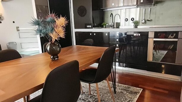 A modern kitchen with black cabinets, a wooden dining table, and black chairs. - Bella Vita - Apartment with free parking (Zagreb)