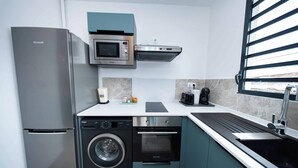 A compact kitchen with a stainless steel refrigerator, a microwave, a dishwasher, and an oven.
