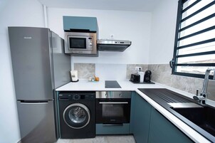 Una cocina compacta con refrigerador de acero inoxidable, microondas, lavavajillas y horno.