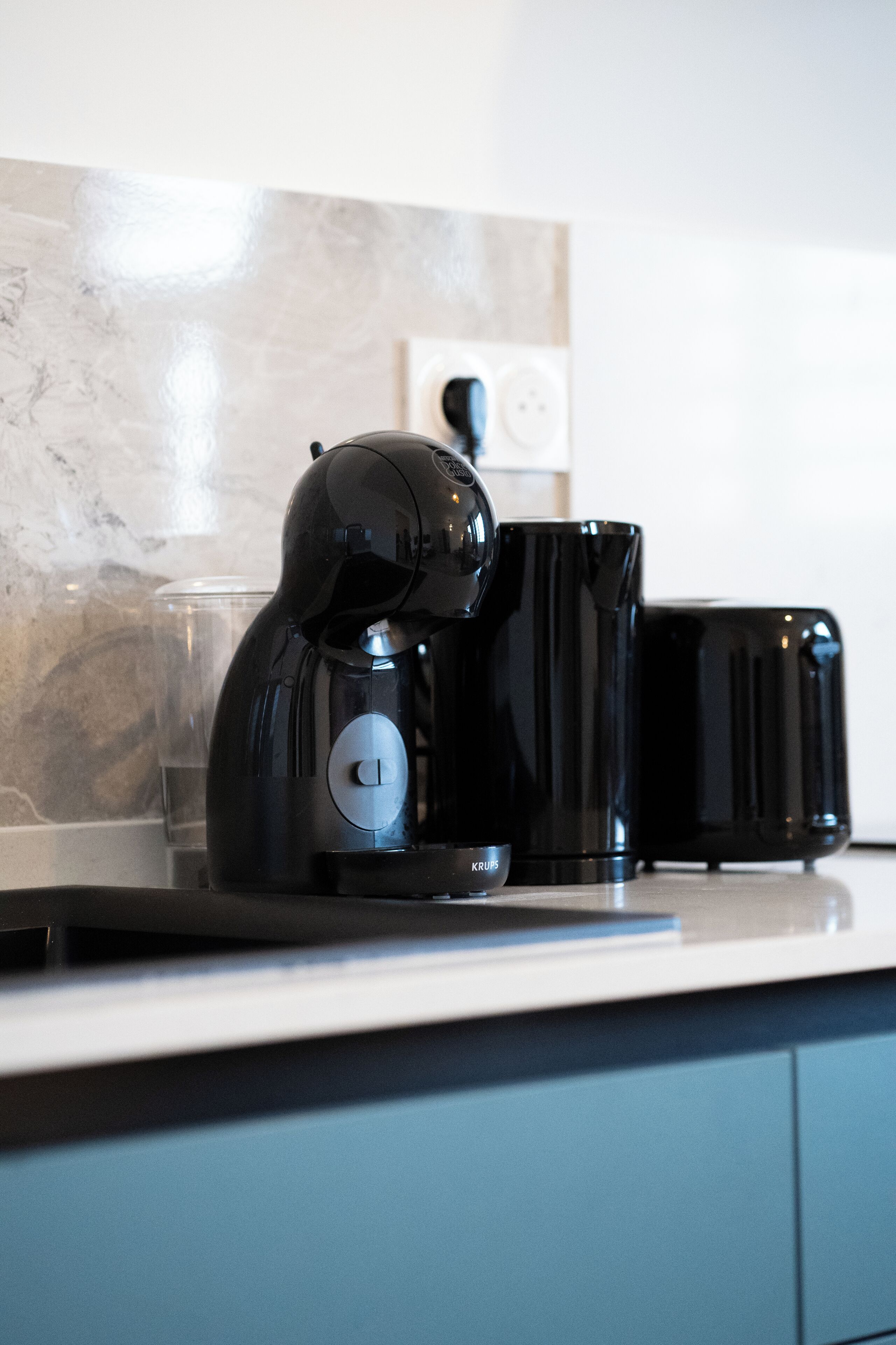 Una cafetera, un vaso y un tostador sobre la encimera de la cocina.