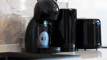 Una cafetera, un vaso y un tostador sobre la encimera de la cocina.