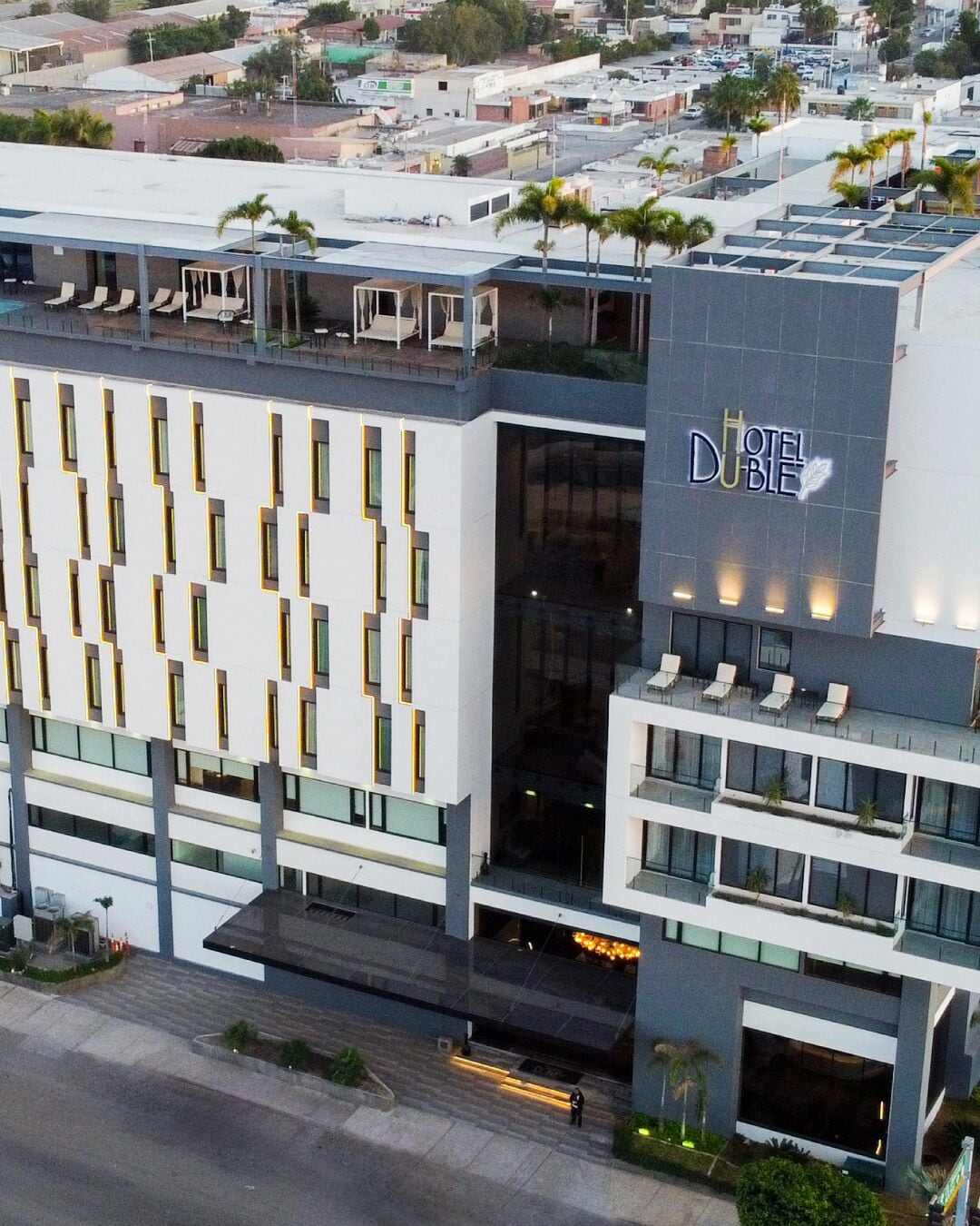 A modern hotel building with a prominent 'DUBBLE' sign, multiple balconies, and a rooftop terrace.