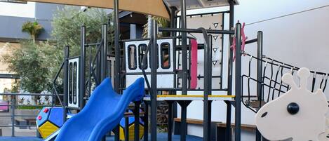 A children's play area with a slide, climbing structures, and a giraffe decoration.