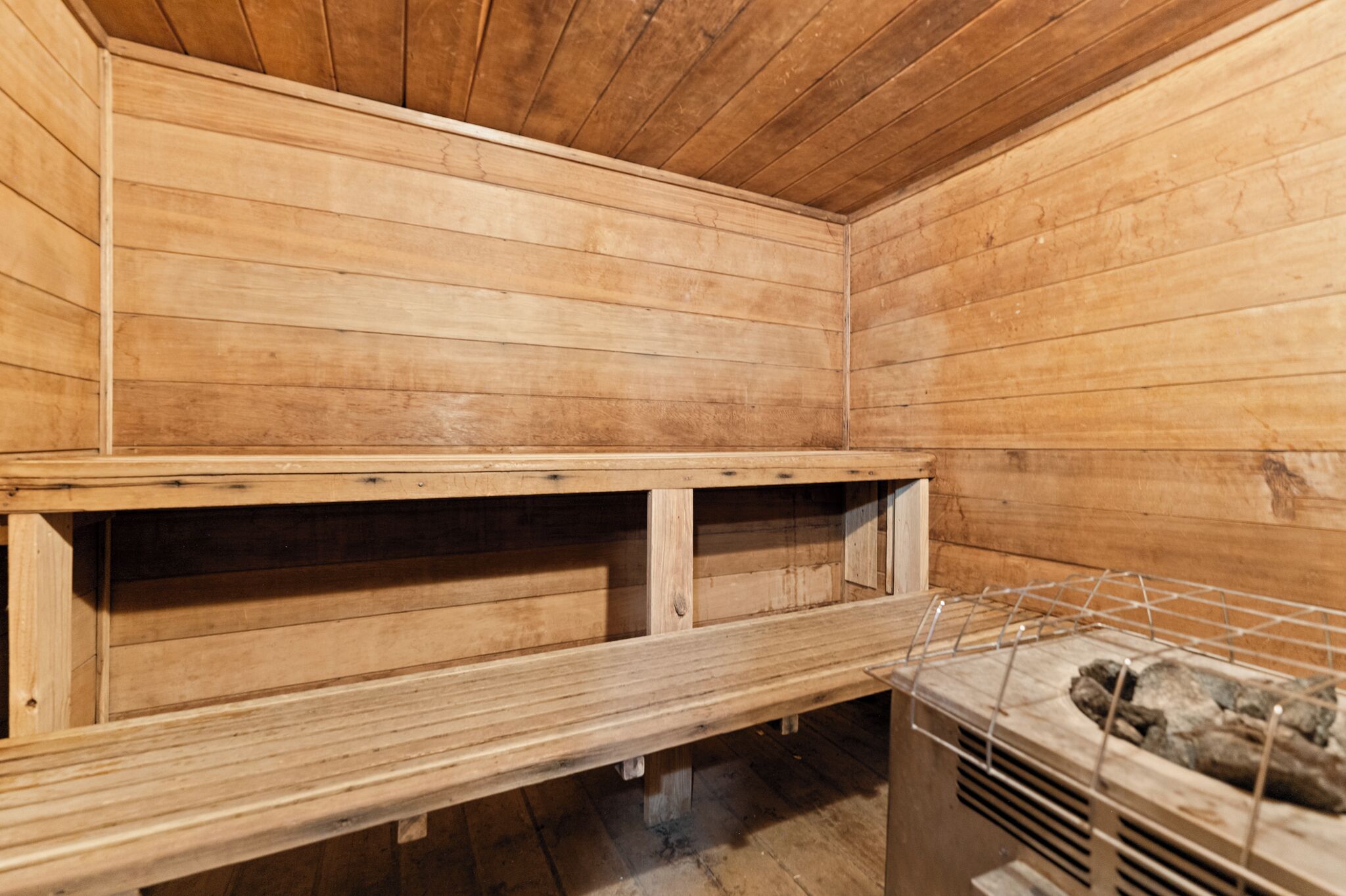 A wooden sauna with benches and a metal rack.