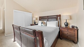 Une chambre à coucher avec un grand lit, une table de chevet, une commode et une armoire.