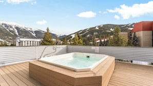 Un bain à remous sur une terrasse en bois avec vue sur les montagnes.