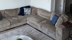 Ein modernes Wohnzimmer mit einer Eckcouch, einem Couchtisch und einem Gemälde an der Wand.