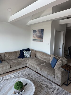 A modern living room with a sectional sofa, a coffee table, and a painting on the wall. - Spacious 4-bedroom house in enchanting Atlantic City with AC (Atlantic City)