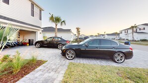 A residential driveway with two parked cars, a garage, and a well-maintained lawn. - Cozy & Spacious 5BR 4.5B Furnished Home w/ Loft & Large Backyard (North Fort Myers)