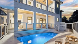 Ein zweistöckiges Haus mit Schwimmbad, Außenmöbeln und einer überdachten Terrasse.