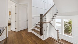 Eine Treppe mit Holzstufen und weißen Geländern, die zu einer Aussichtsplattform mit Blick auf Grünfläche führt.