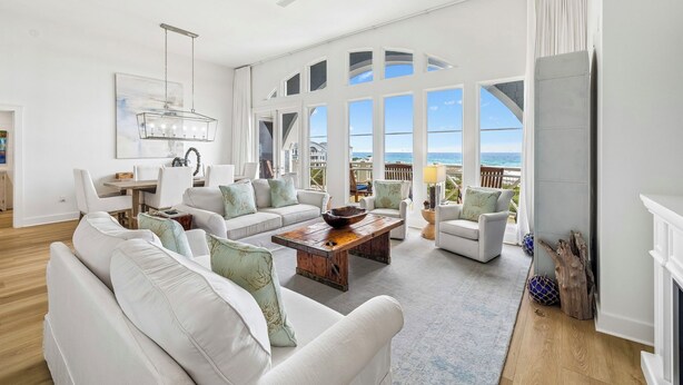 A spacious living room with white furniture, a wooden coffee table, and large windows offering ocean views. - Top-Floor Gulf Views and Beach Access (Seacrest)