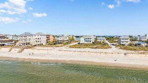 Ein strandnahes Anwesen mit mehreren Gebäuden, einem Sandstrand und blauem Himmel.