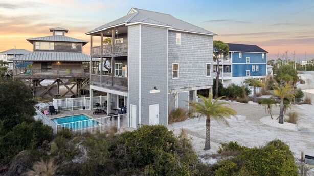Ein Strandhaus mit zwei Etagen, einem Pool, mehreren Balkonen und Blick aufs Meer.