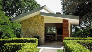 A modern house with a stone exterior, a wooden door, and a patio with a table and chairs. - Charming 2-bedroom apartment with AC in peaceful Río Oro (Río Oro)